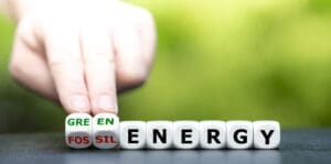 Hand turns dice and changes the expression 'fossil energy' to 'green energy'